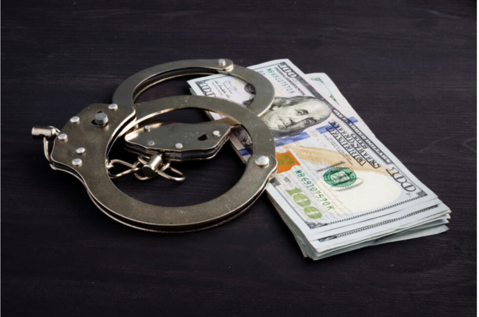 Affordable Bail Bonds in Tulsa A stack of money with a set of handcuffs on top of a desk.